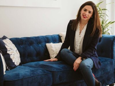 Mujer sonriente en el sofá azul de asesoramiento jurídico-financiero de Empresas en España