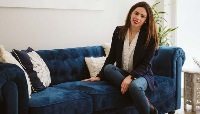 Mujer sonriente en el sofá azul de asesoramiento jurídico-financiero de Empresas en España